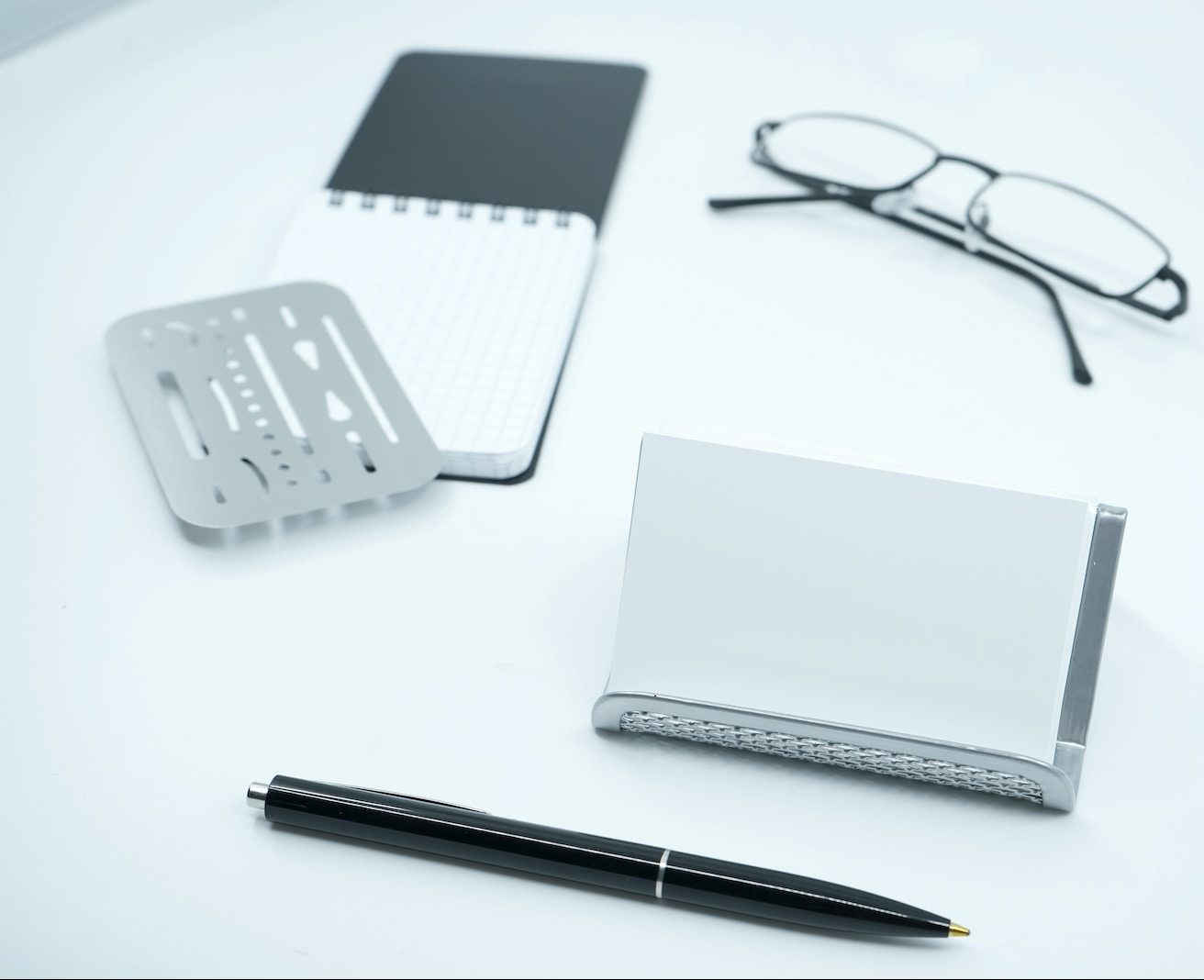 black framed eyeglasses beside white printer paper and black pen